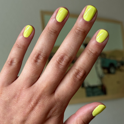 Hand with nails painted bright electric yellow Game Set Mani polish for a glossy quick-dry manicure look at home