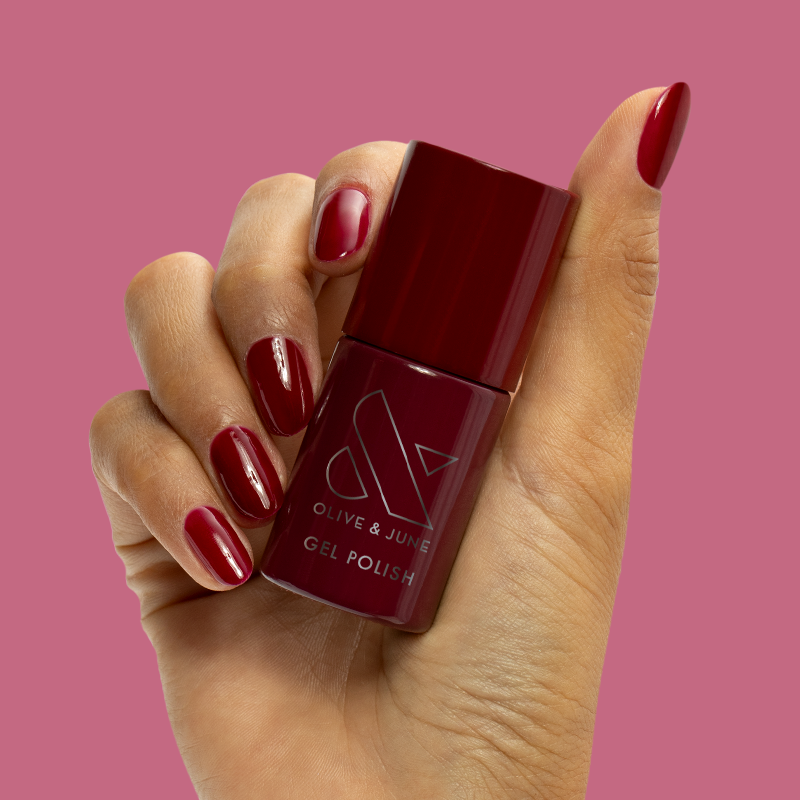 Mulberry - Gel bottle held with polished nails in deep maroon for a rich, long-lasting manicure by Olive and June