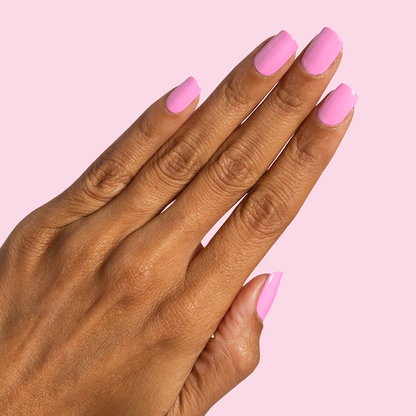 Hand with Taffy bright pink quick dry gel polish on neatly manicured nails against pale pink background